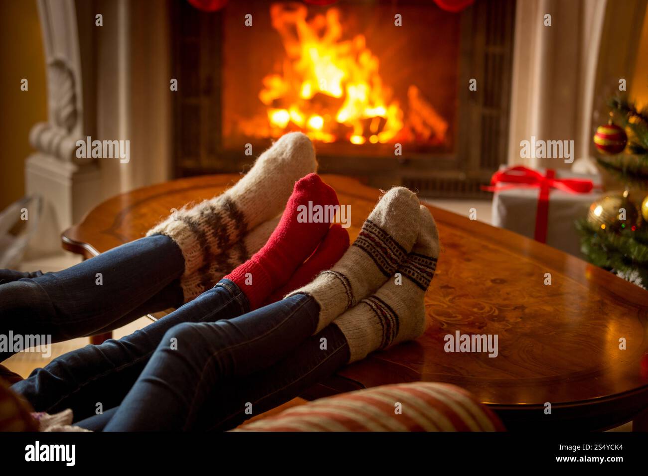 Pieds mâles et femelles dans des chaussettes en laine se réchauffant à la cheminée en feu Banque D'Images Pieds mâles et femelles dans des chaussettes en laine se réchauffant à la cheminée en feu Banque D'Images