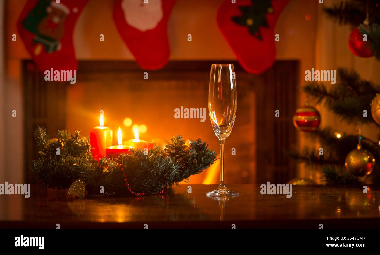 Flûte à champagne sur la table du dîner de Noël devant la cheminée en feu Banque D'Images