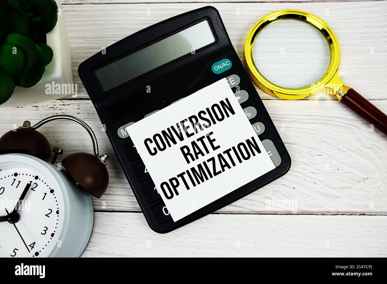 Message texte d'optimisation du taux de conversion sur note autocollante avec loupe, réveil et calculatrice sur fond en bois Banque D'Images