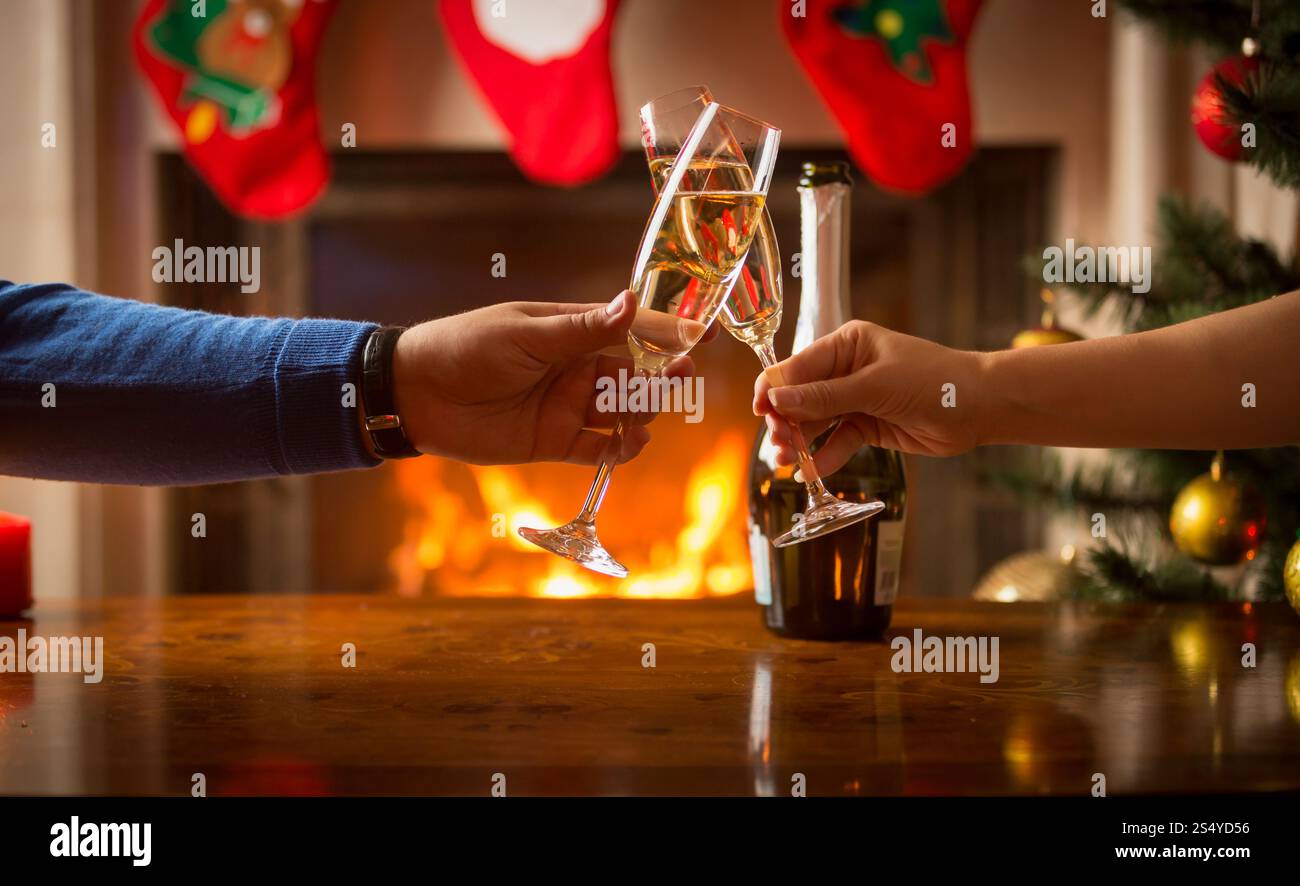 L'homme et la femme ayant le dîner de Noël et clinking glasses à côté d'une cheminée Banque D'Images