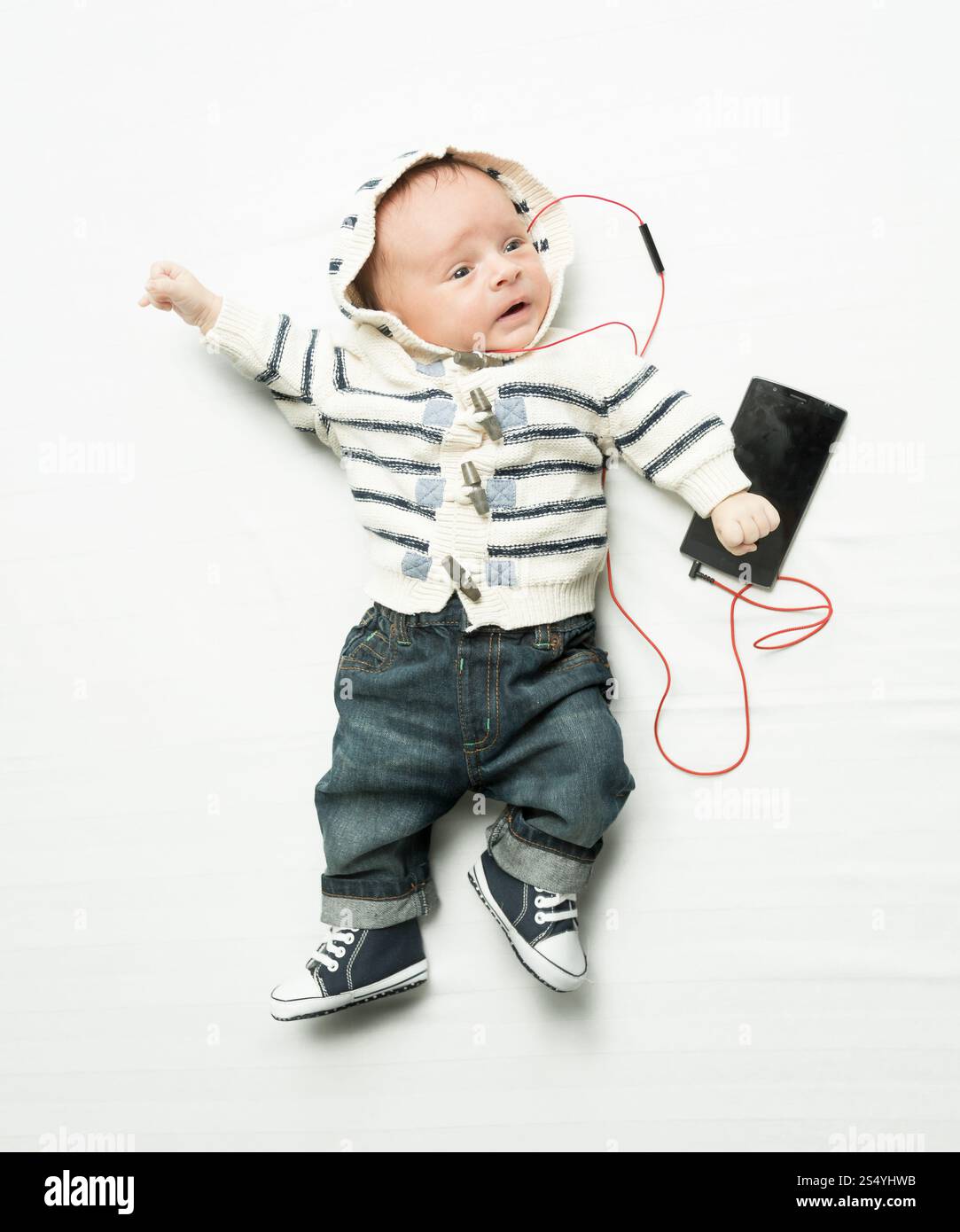 Mignon bébé garçon écoutant de la musique sur le téléphone avec des écouteurs Banque D'Images