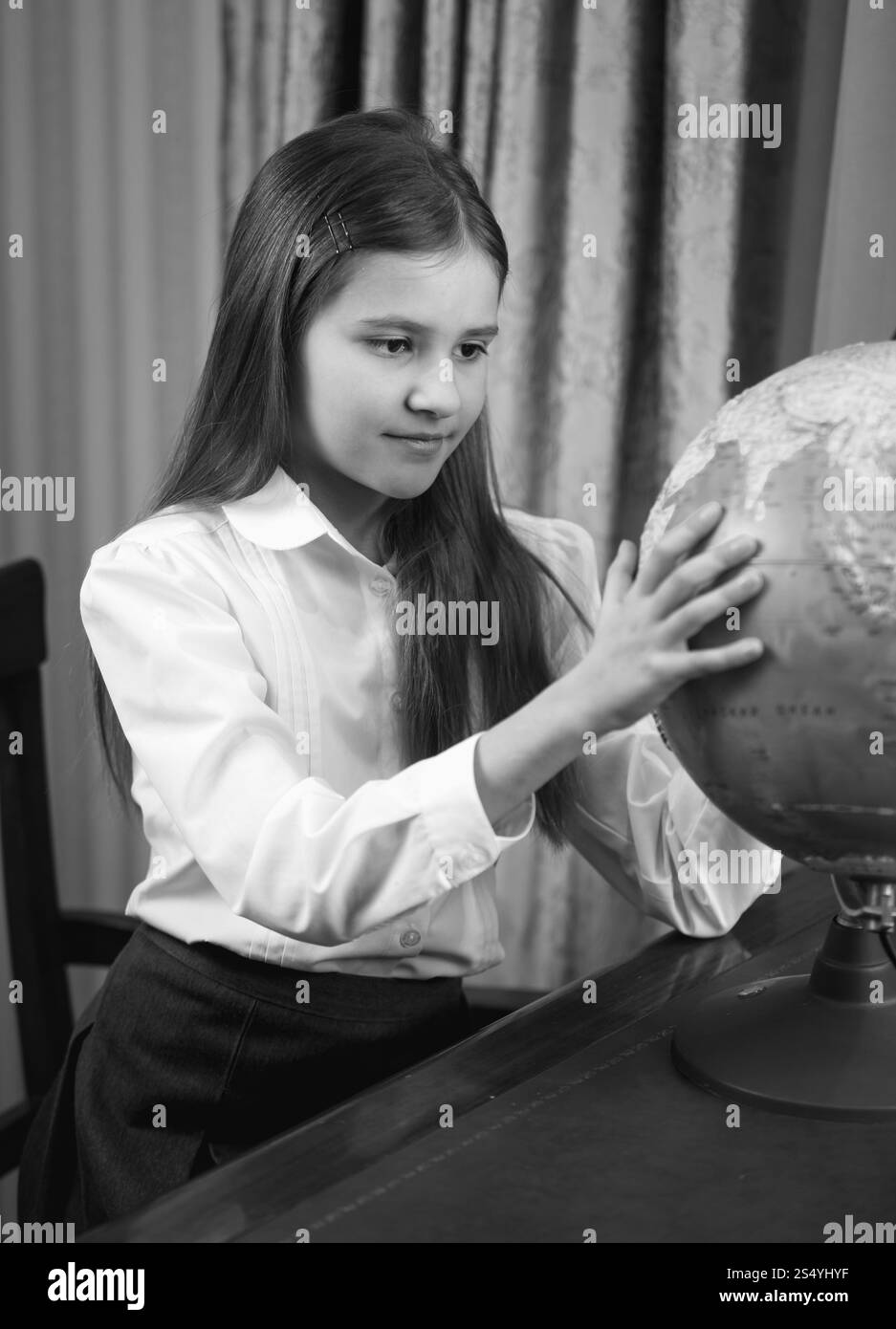 Portrait en noir et blanc d'une écolière mignonne regardant le grand globe Banque D'Images