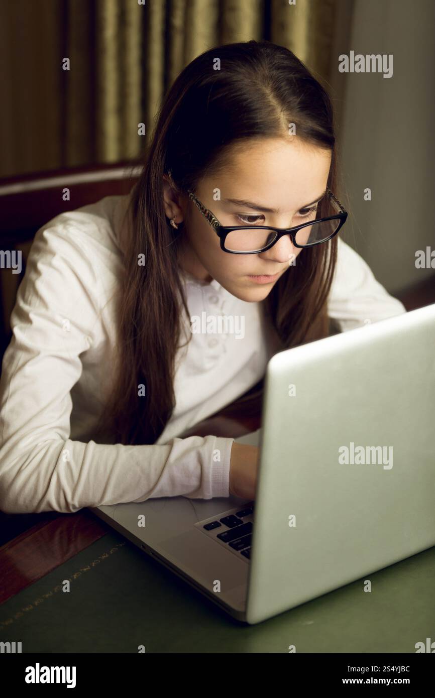 Portrait de belle adolescente dans des lunettes à l'aide d'un ordinateur portable Banque D'Images
