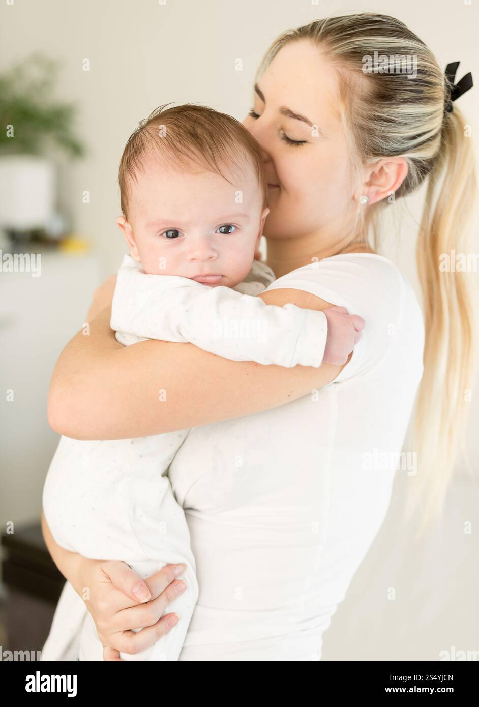 Jeune belle femme embrassant son bébé garçon sur les mains Banque D'Images
