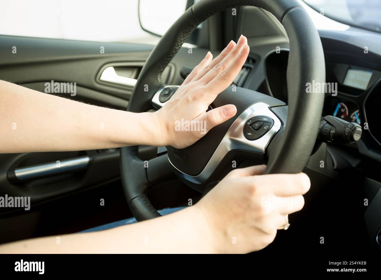 Gros plan de la femme agacée conduisant une voiture et klaxonnant Banque D'Images