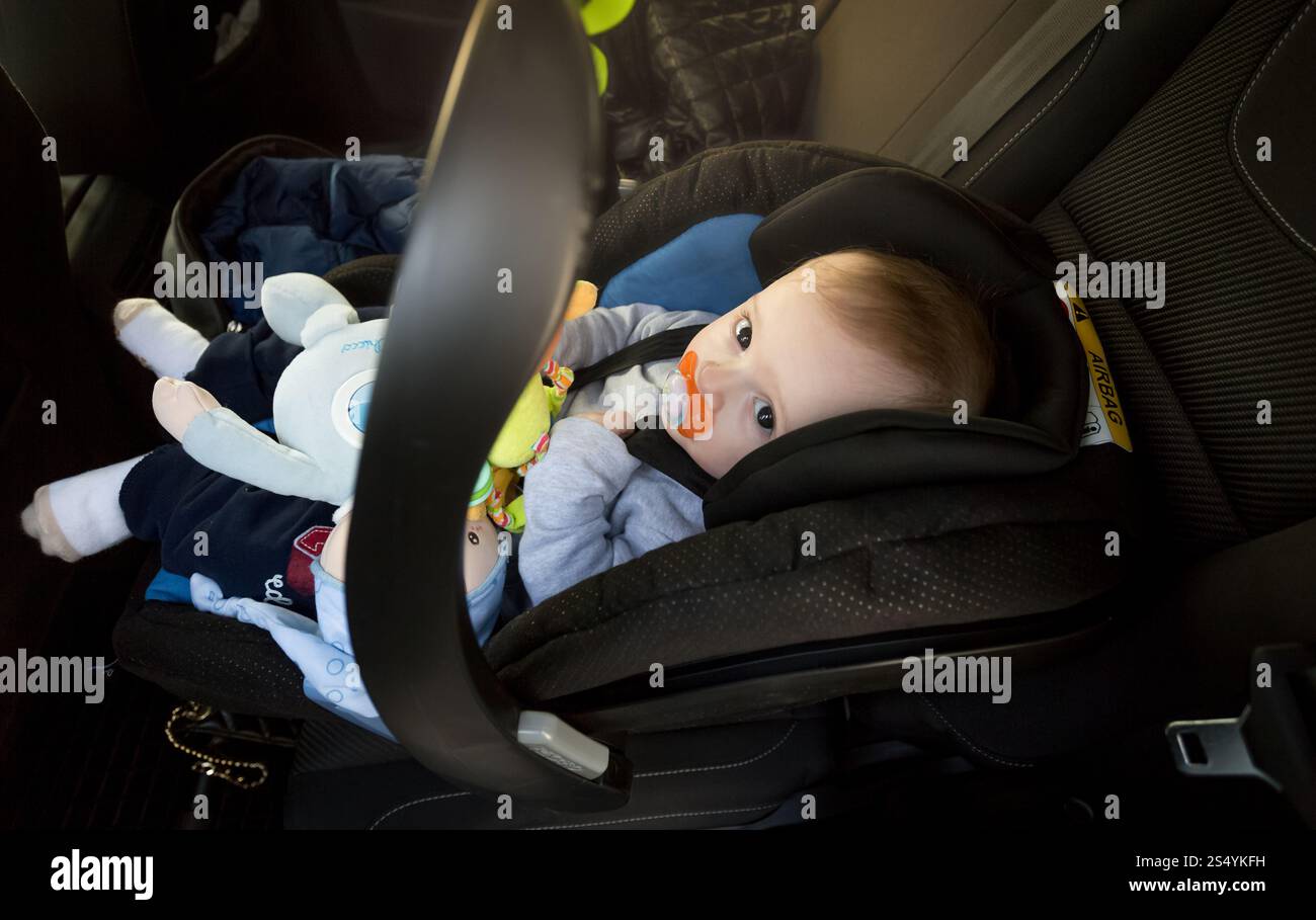 Mignon bébé garçon assis dans le siège de sécurité bébé à la voiture Banque D'Images