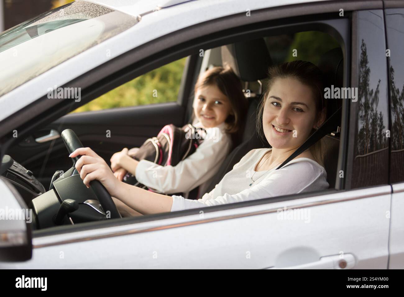 Portrait d'une mère souriante emmenant sa fille à l'école en voiture Banque D'Images