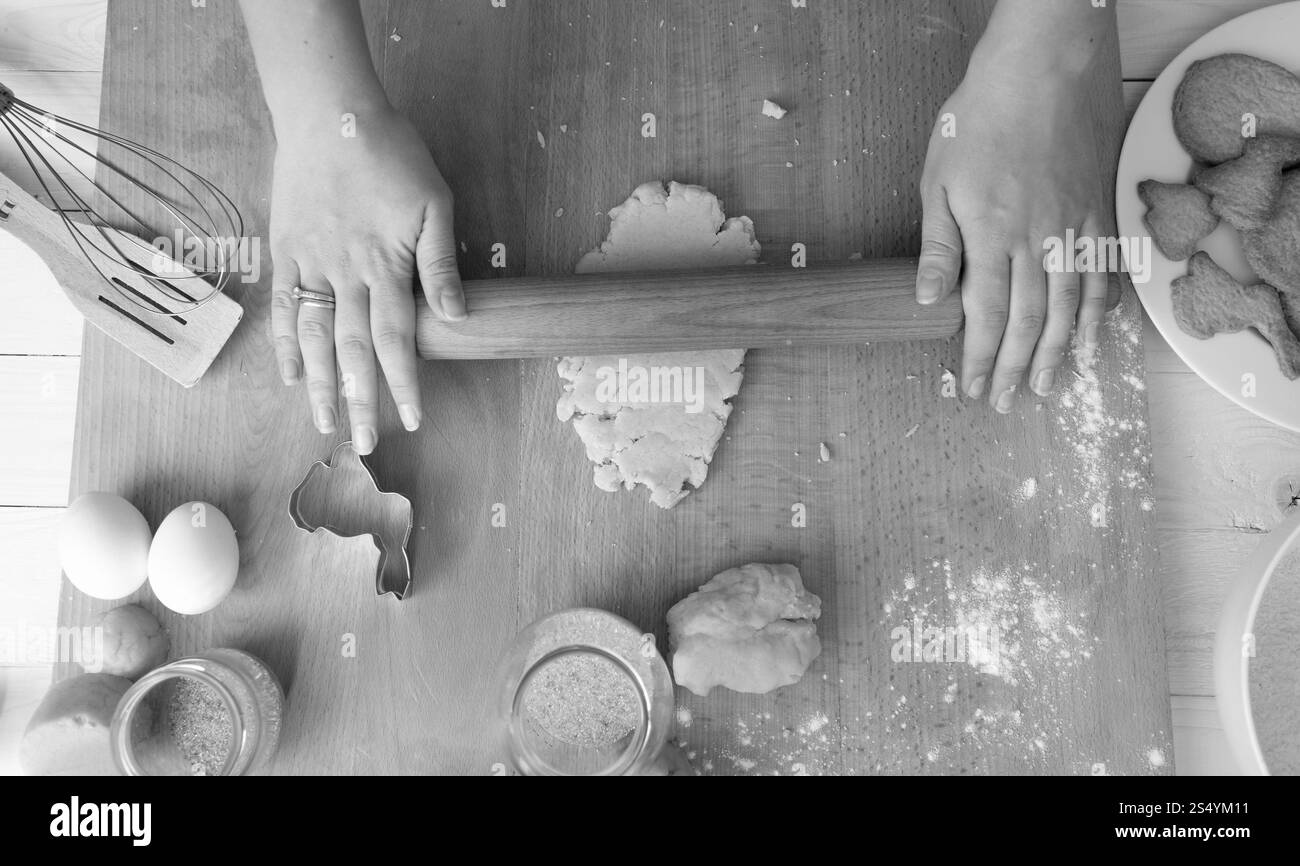 Image en noir et blanc d'en haut sur la femme préparant la pâte pour les biscuits de vacances Banque D'Images