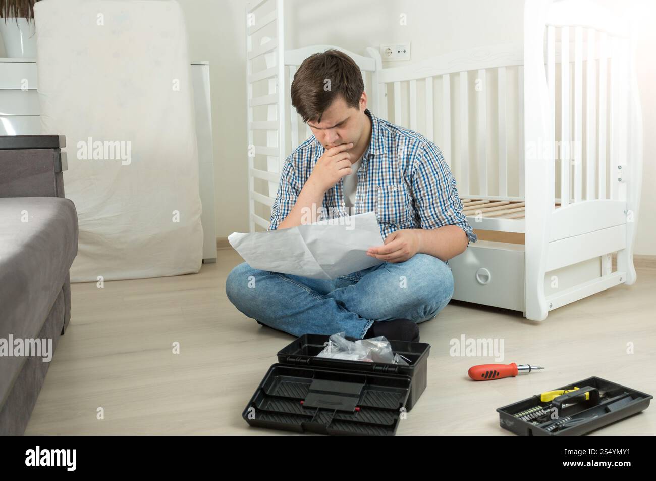 Homme confus de l'assemblage de meubles de lecture manuel Banque D'Images