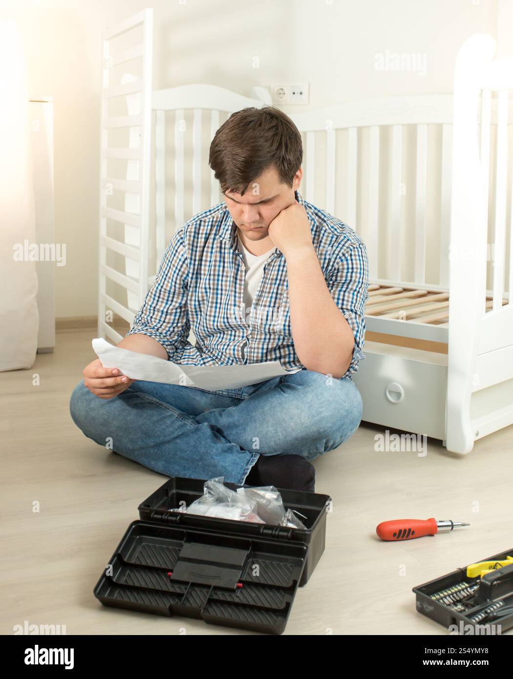 Homme confus au sujet de l'assemblage de meubles de lecture manuel Banque D'Images