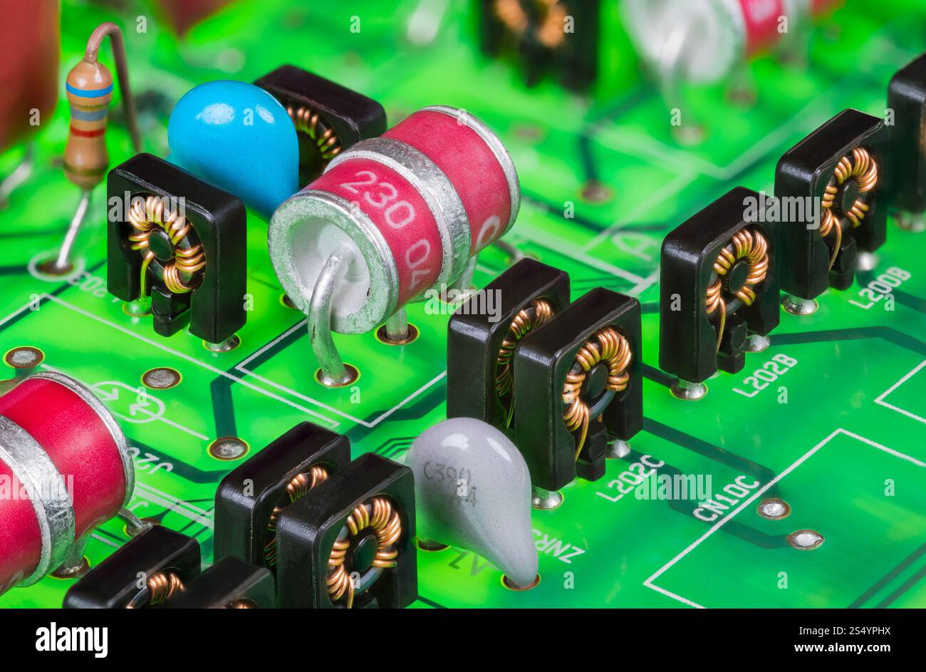 Parasurtenseurs à décharge gazeuse à électrode rouge et inductances toroïdales dans un boîtier noir. Gros plan des composants électroniques sur le détail vert de la carte de circuit imprimé. Banque D'Images
