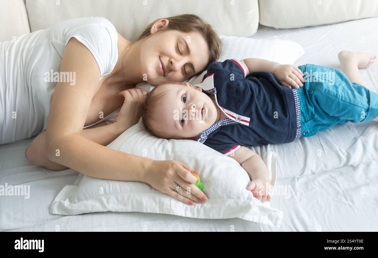 Portrait de mère dormant sur oreiller avec son tout-petit Banque D'Images