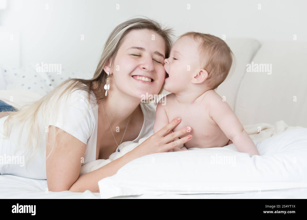 Portrait d'une mère joyeuse embrassant et embrassant son bébé garçon sur le lit Banque D'Images