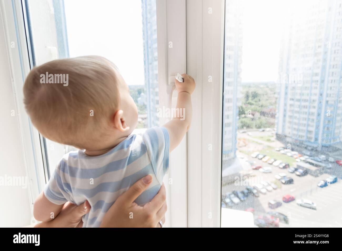 Mère tenant bébé garçon alors qu'il regarde dehors par la fenêtre Banque D'Images