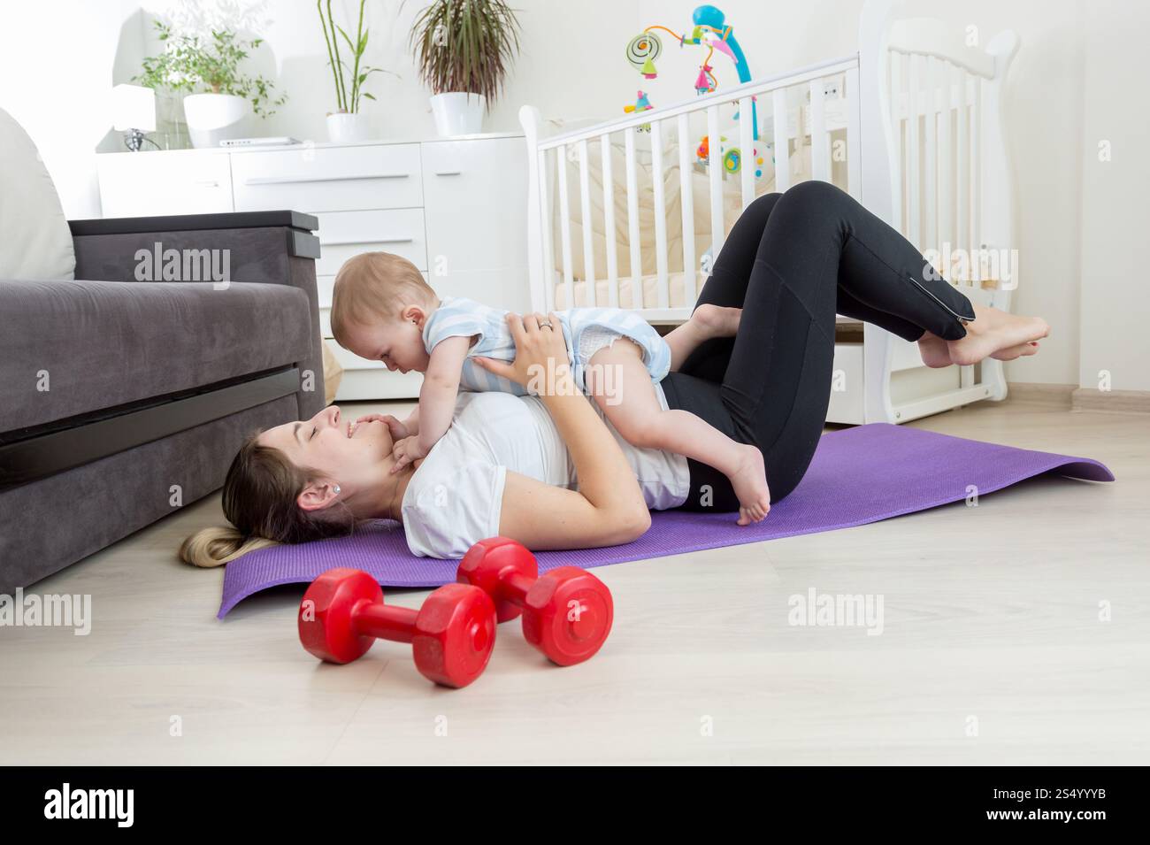 Heureuse mère faisant de l'exercice à la maison et s'amusant avec son bébé garçon Banque D'Images