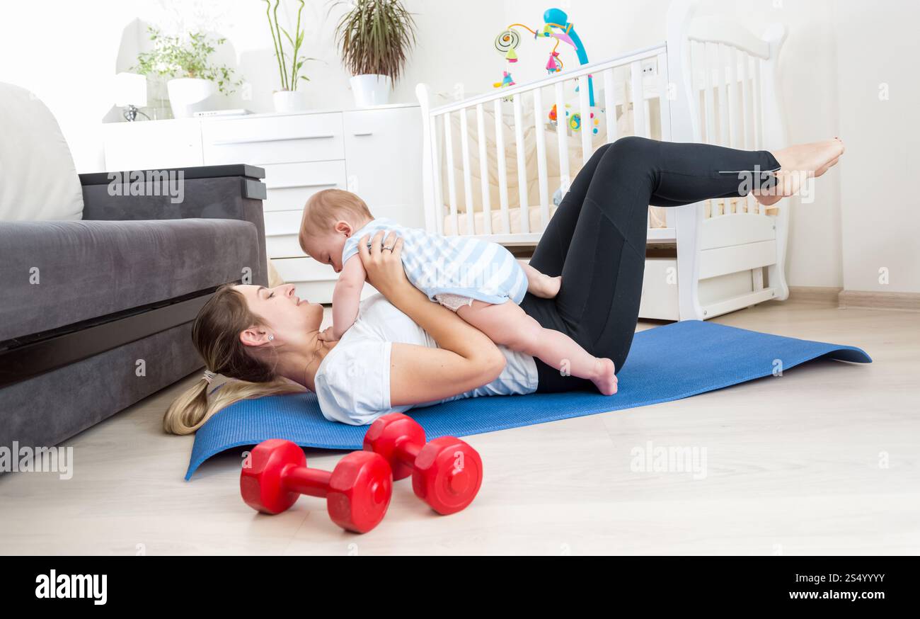 Heureuse mère faisant de l'exercice à la maison et s'amusant avec son bébé garçon Banque D'Images