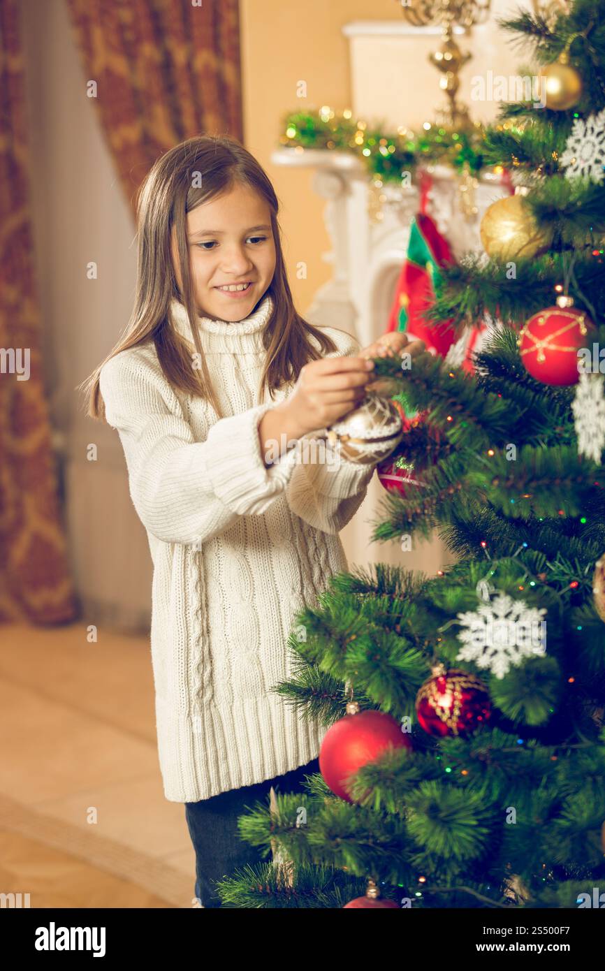 Joyeuse belle fille décorant l'arbre de Noël avec des boules Banque D'Images