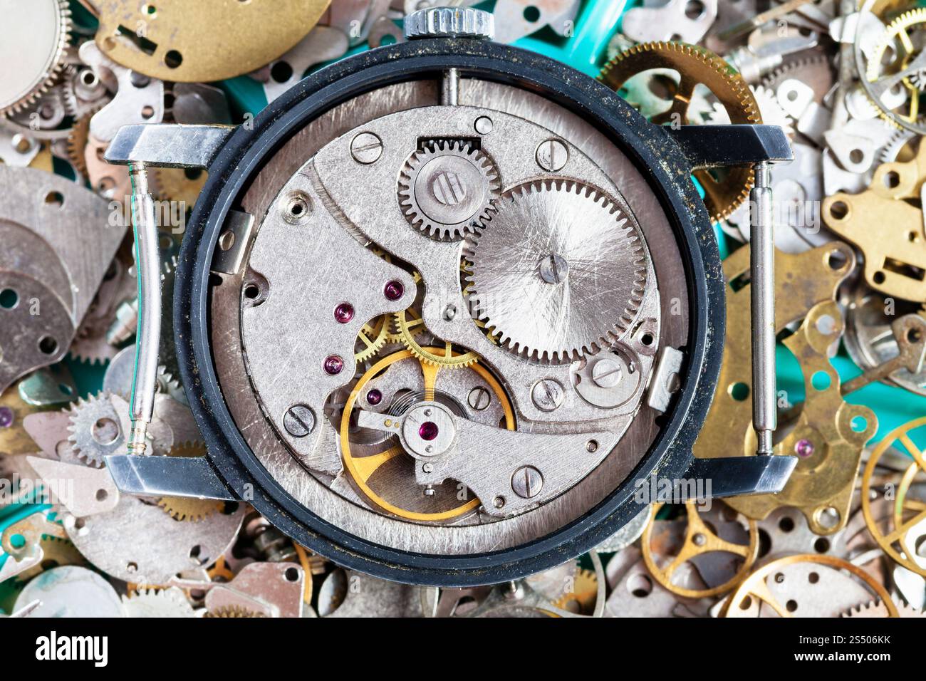 atelier horloger - montre-bracelet vintage ouverte sur un tas de pièces de rechange d'horloge Banque D'Images