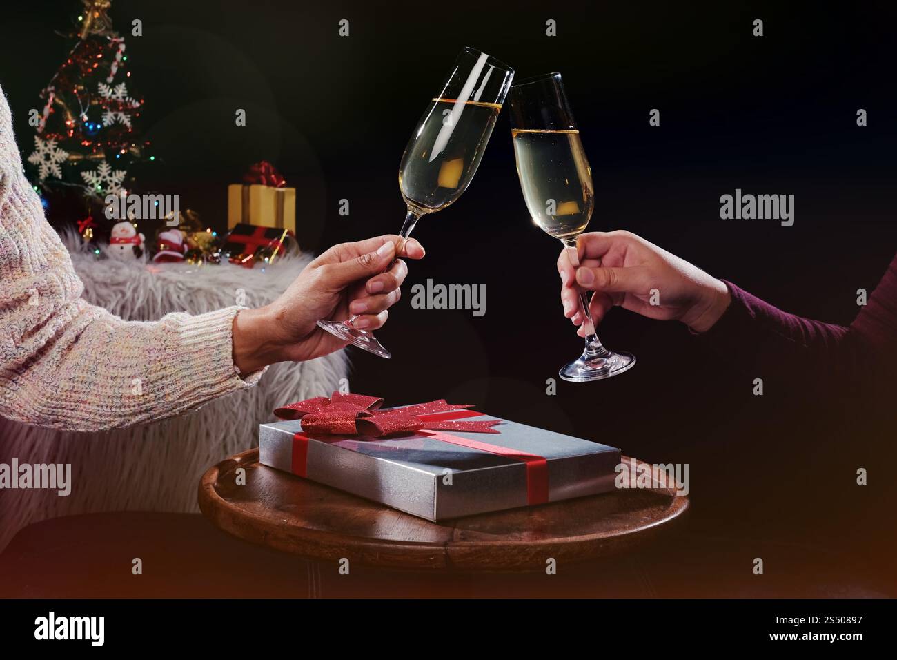 Noël ou Nouvel An fête personnes mains avec verres de cristal pleine de champagne près de l'arbre de Noël et de l'espace pour votre texte Banque D'Images