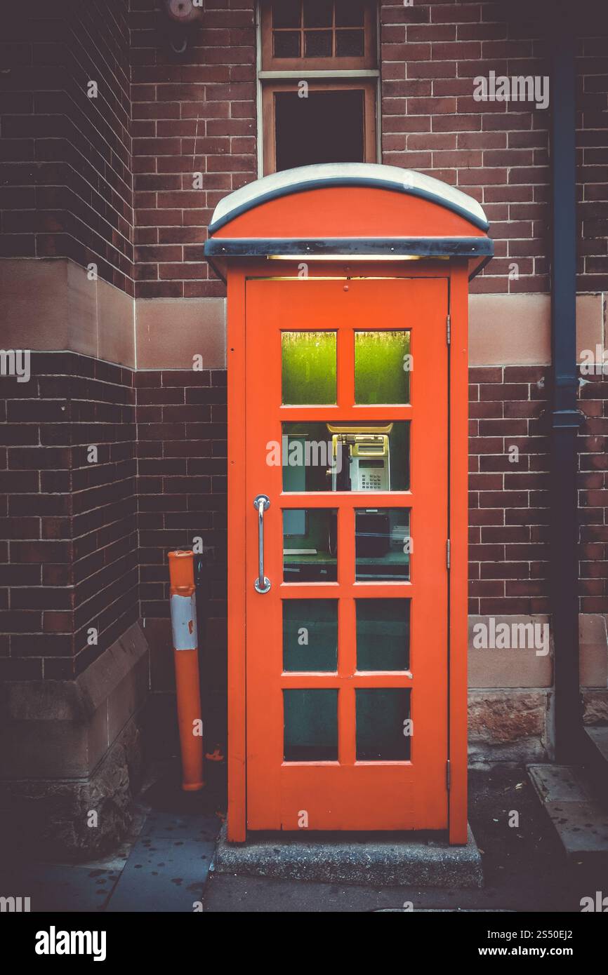 Cabine téléphonique rouge britannique vintage devant un mur de briques. Cabine téléphonique rouge Royaume-Uni vintage Banque D'Images