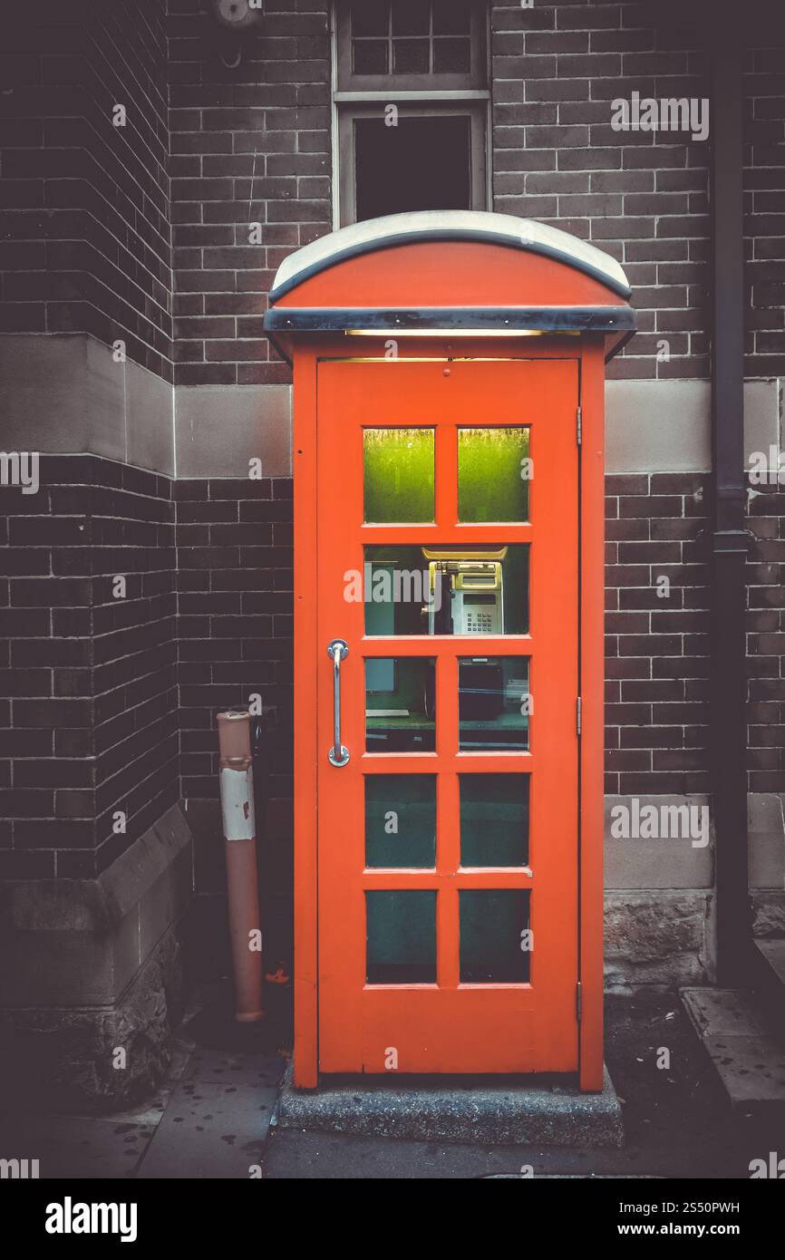 Cabine téléphonique rouge britannique vintage devant un mur de briques. Cabine téléphonique rouge Royaume-Uni vintage Banque D'Images