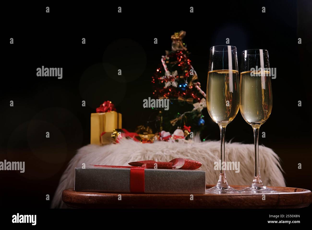 Noël ou Nouvel An fête personnes mains avec verres de cristal pleine de champagne près de l'arbre de Noël et de l'espace pour votre texte Banque D'Images