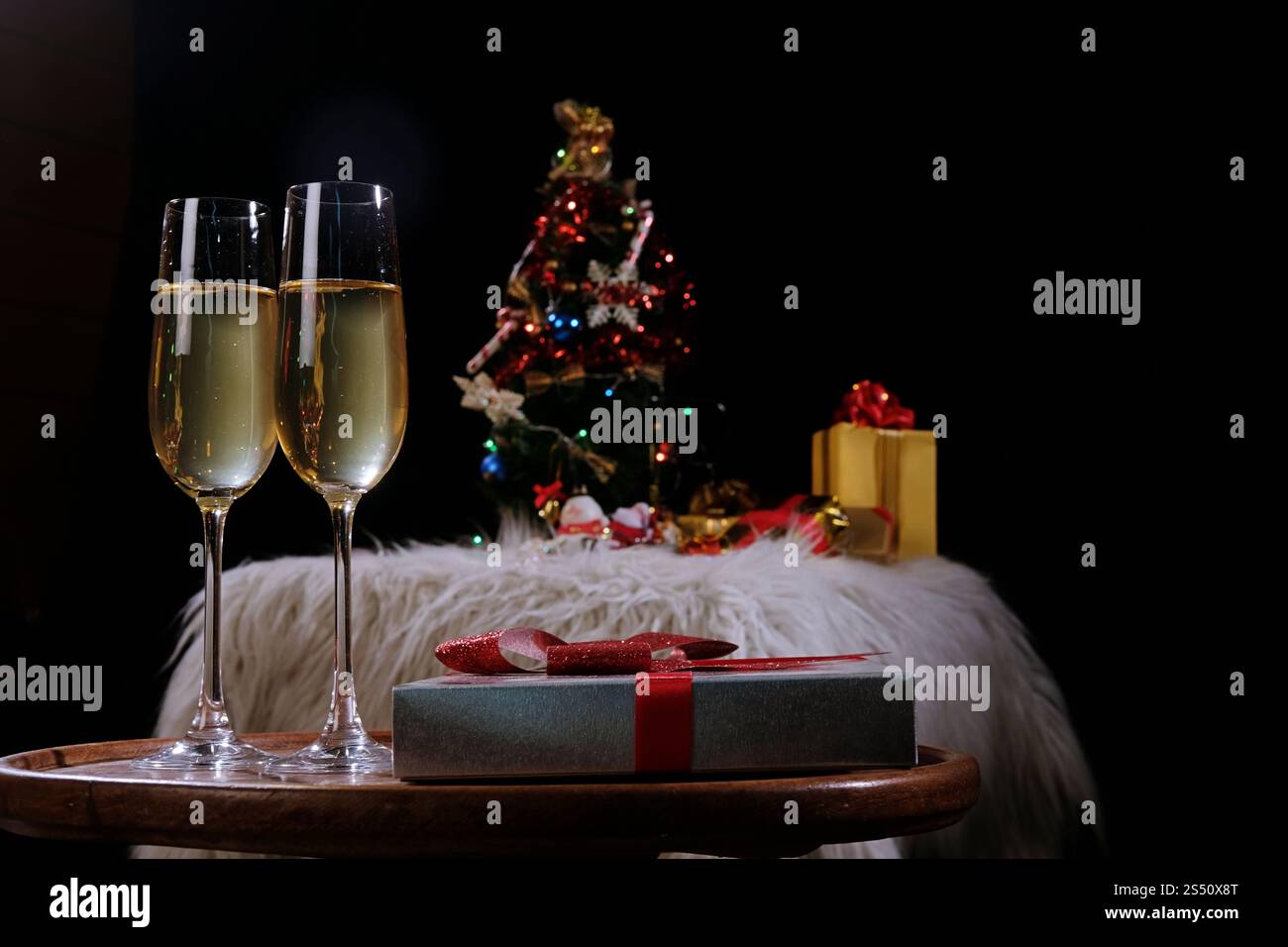 Noël ou Nouvel An fête personnes mains avec verres de cristal pleine de champagne près de l'arbre de Noël et de l'espace pour votre texte Banque D'Images