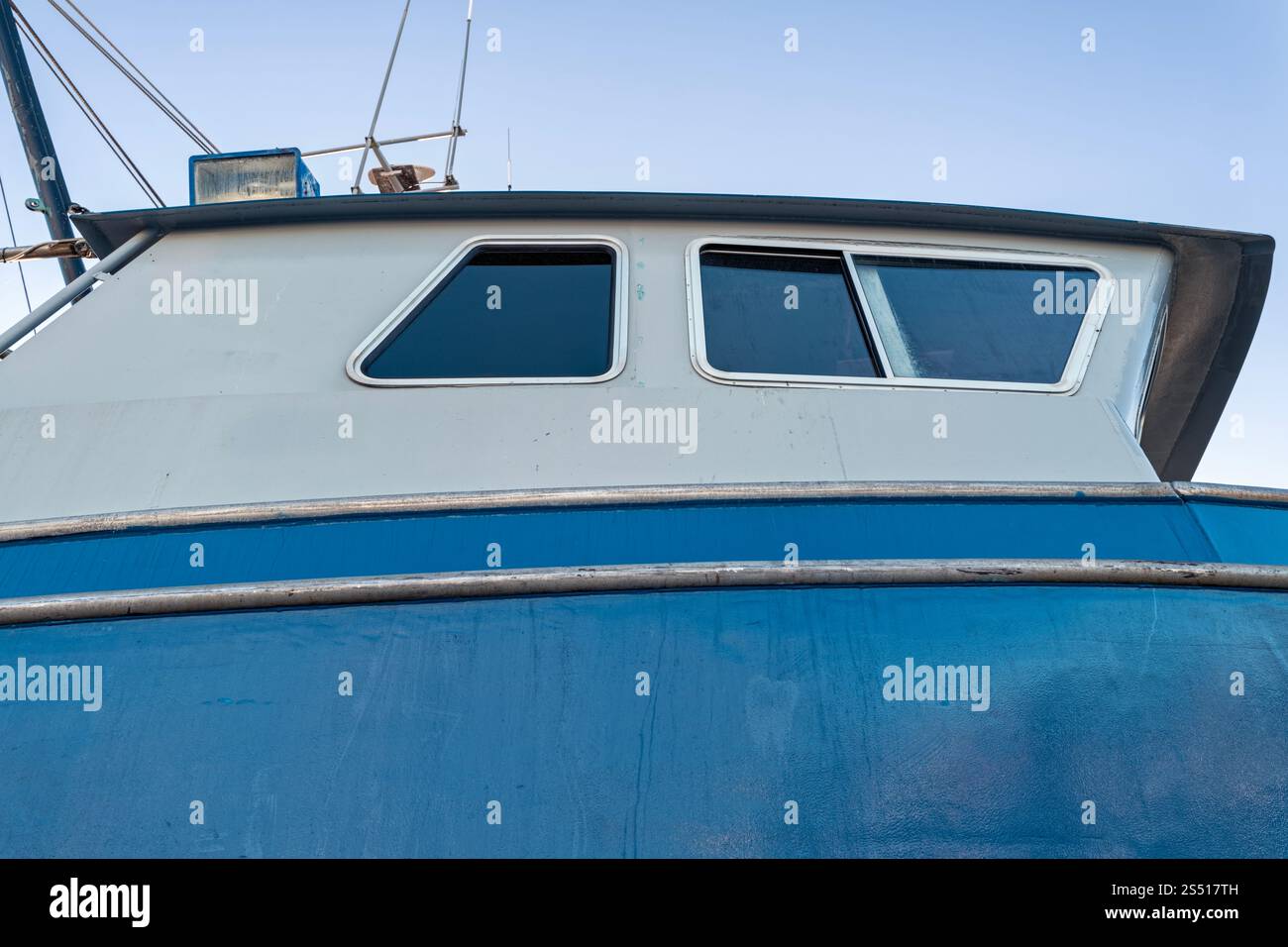 Fenêtres latérales de la cabine d'un bateau de pêche bleu amarré Banque D'Images