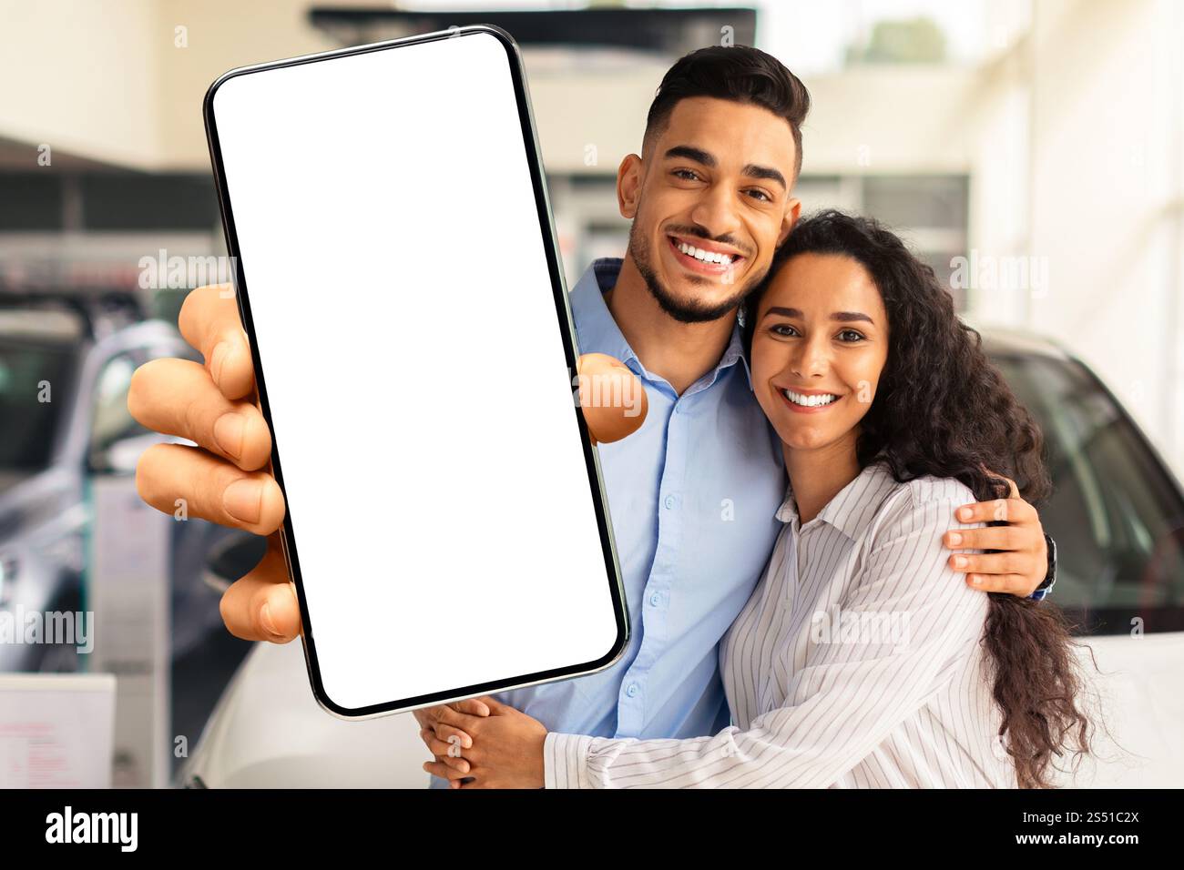 Famille musulmane aimant montrant un smartphone avec écran vierge, achetant la voiture Banque D'Images