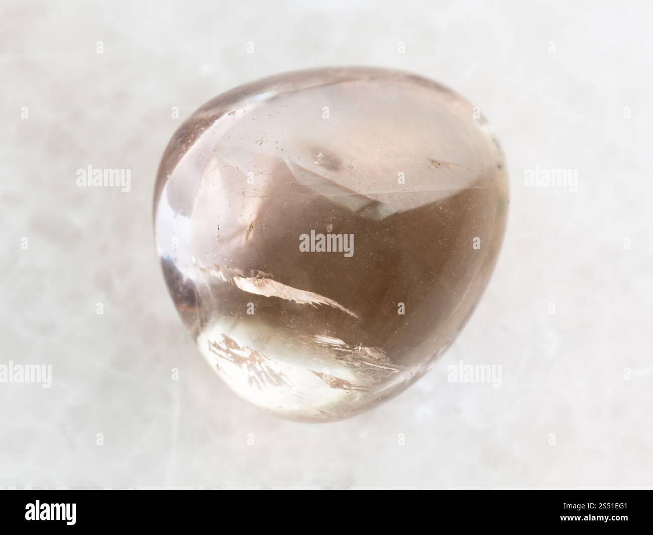 La prise de vue macro des eaux minérales naturelles rock specimen - tumbled quartz fumé gem stone sur fond de marbre blanc Banque D'Images