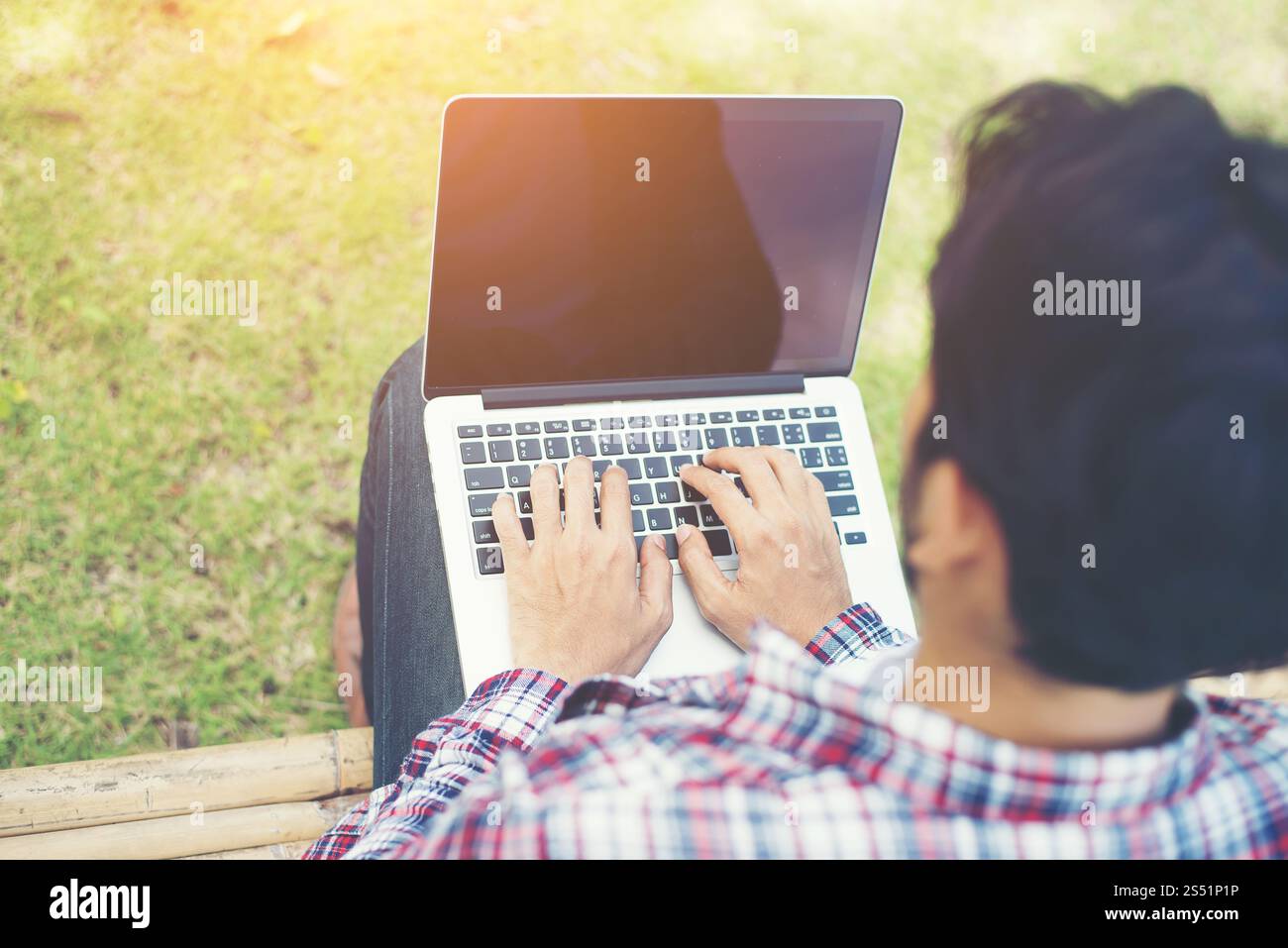 Jeune homme hipster travailler sur ordinateur au parc dans une journée ensoleillée. Banque D'Images Jeune homme hipster travailler sur ordinateur au parc dans une journée ensoleillée. Banque D'Images