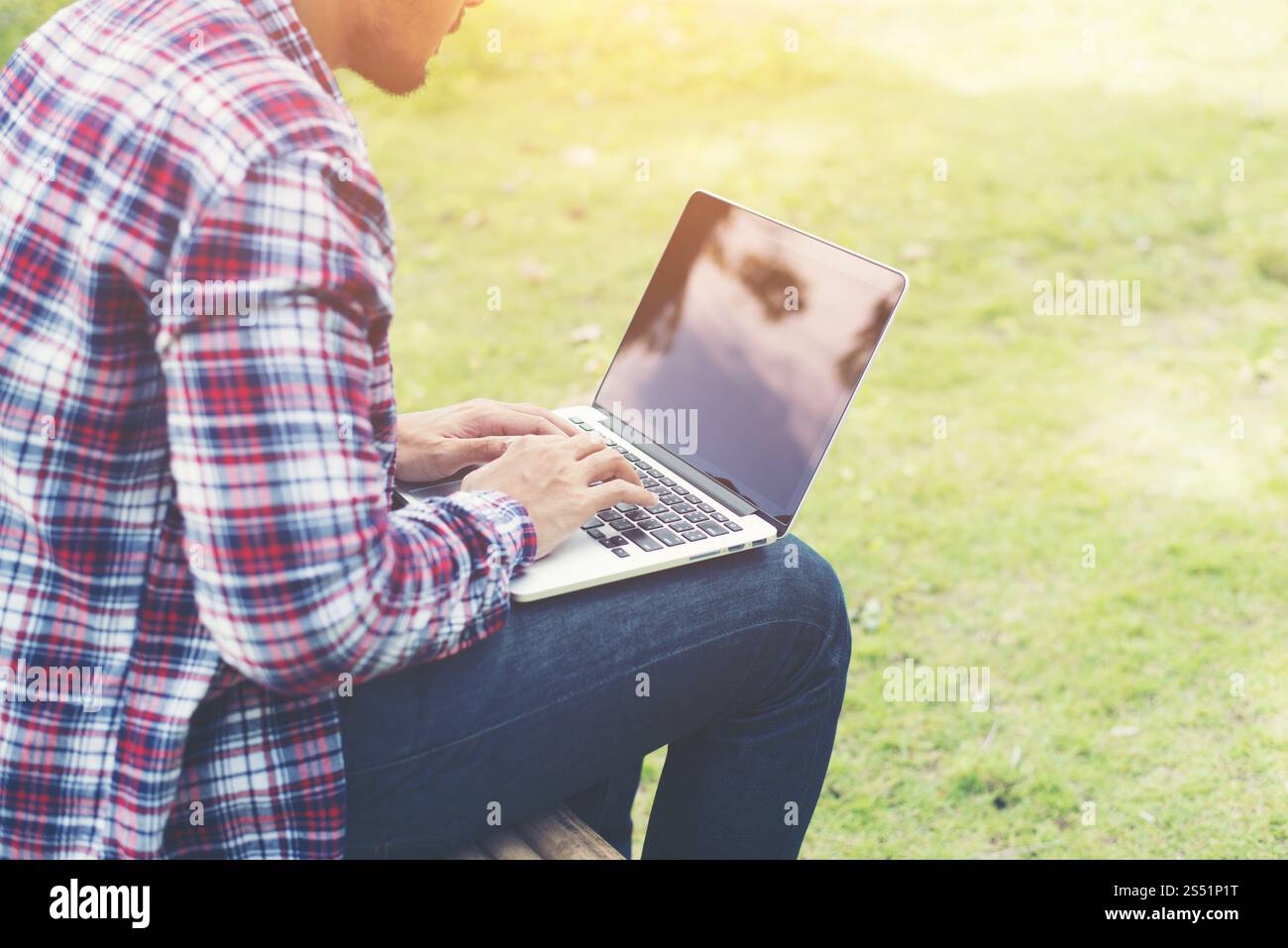 Jeune homme hipster travailler sur ordinateur au parc dans une journée ensoleillée. Banque D'Images Jeune homme hipster travailler sur ordinateur au parc dans une journée ensoleillée. Banque D'Images