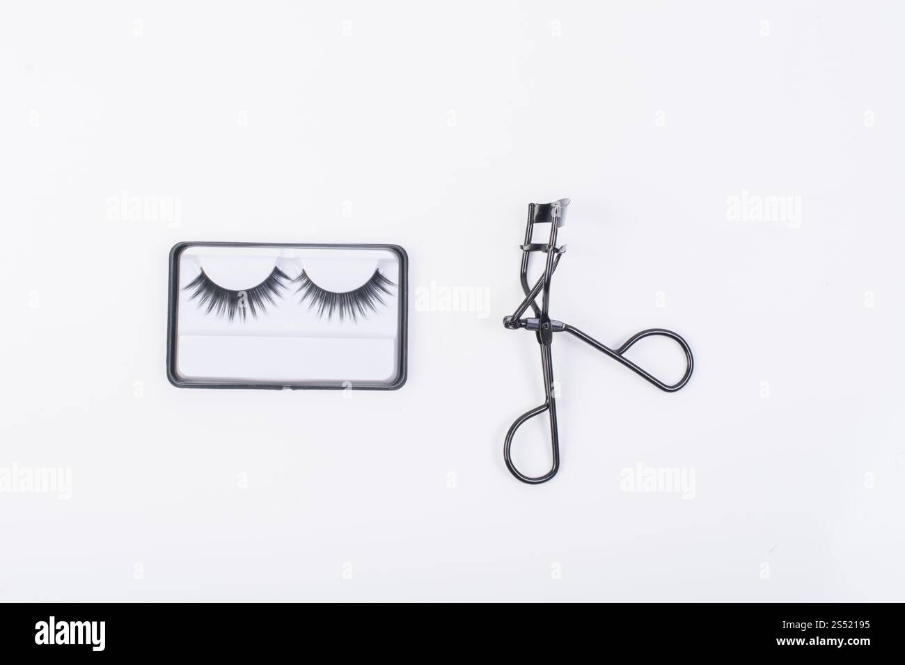 Faux faux cils avec curler isolé sur fond blanc. Banque D'Images