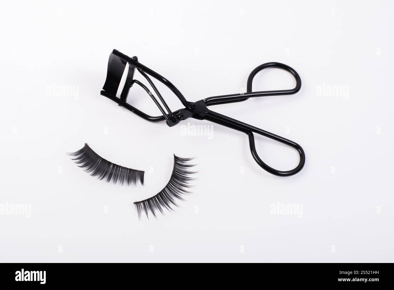 Faux faux cils avec curler isolé sur fond blanc. Banque D'Images