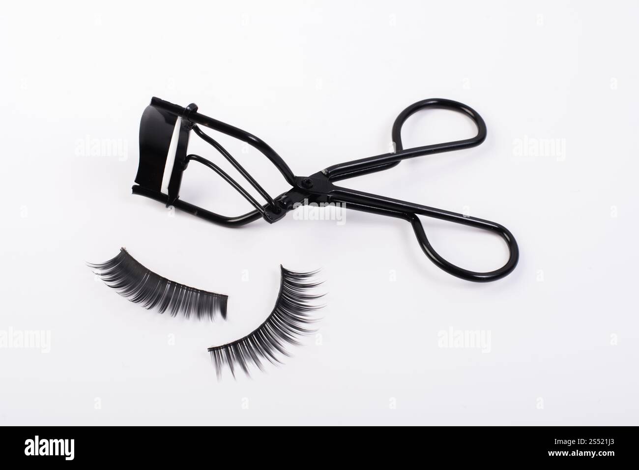 Faux faux cils avec curler isolé sur fond blanc. Banque D'Images