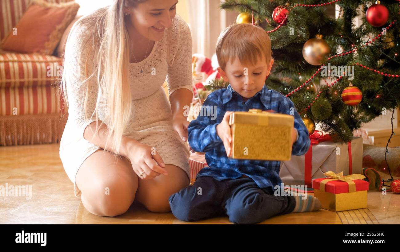 Garçon en bas âge excité avec la mère à la recherche sur le cadeau de Noël. Portrait de garçon en bas âge excité avec la mère regardant sur le cadeau de Noël Banque D'Images