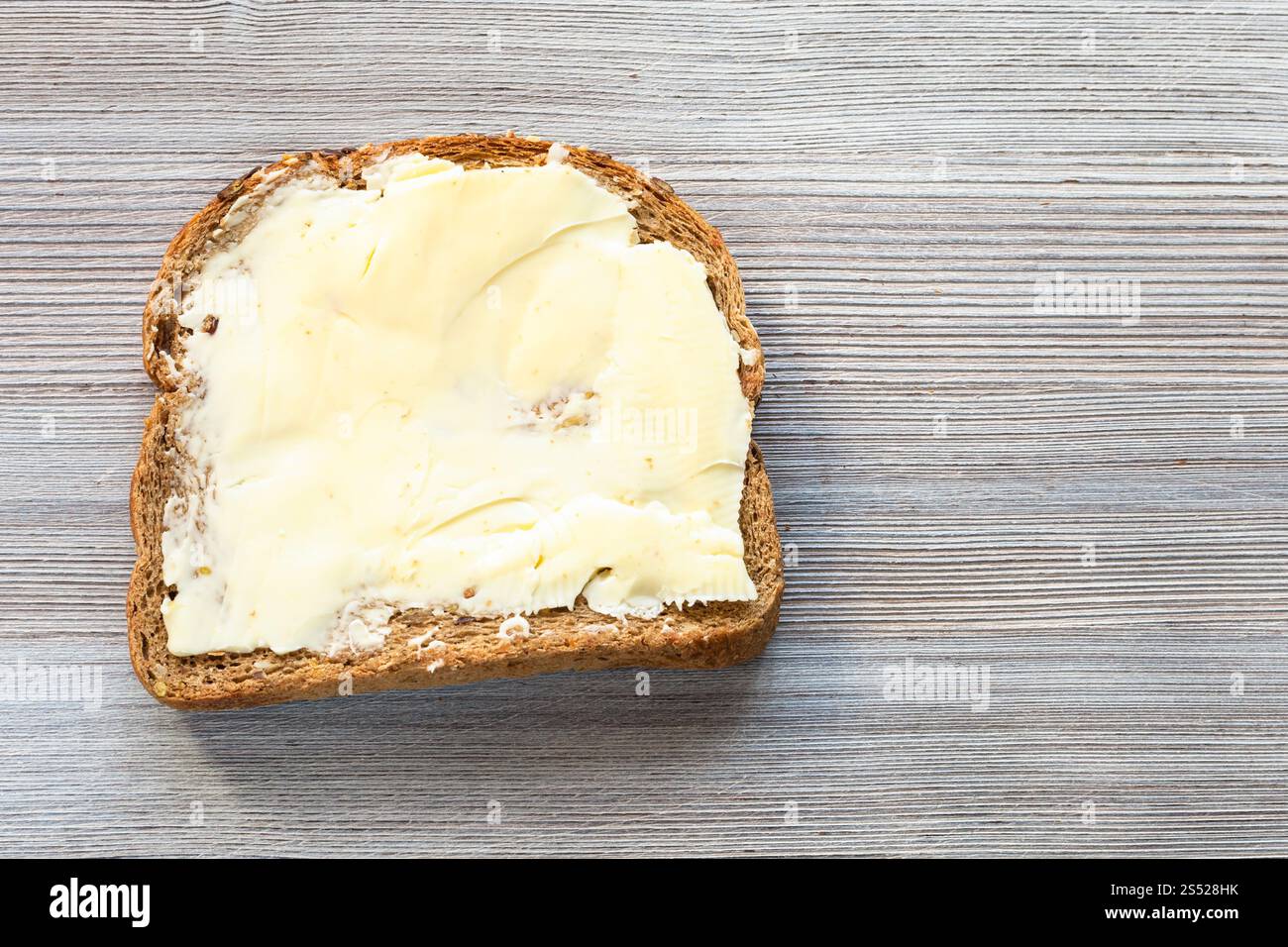 Vue du dessus du pain sandwich avec du beurre beurré sur planche de bois gris blanc avec copyspace Banque D'Images