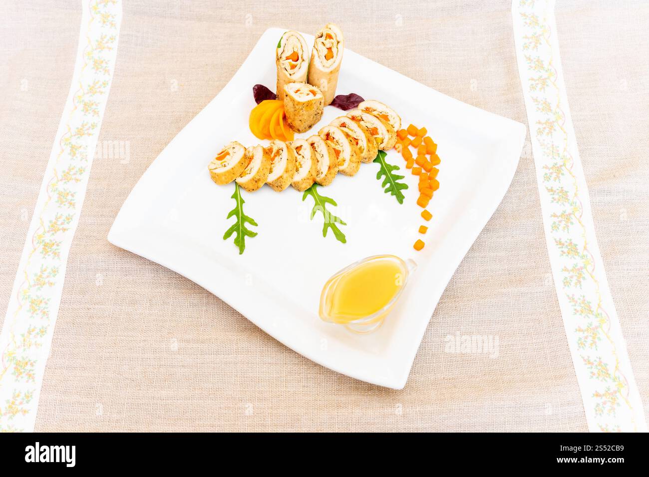 Une assiette magnifiquement agencée avec des rouleaux de sushi avec des ingrédients frais, accompagnés d'une sauce savoureuse. La présentation comprend Decorat Banque D'Images