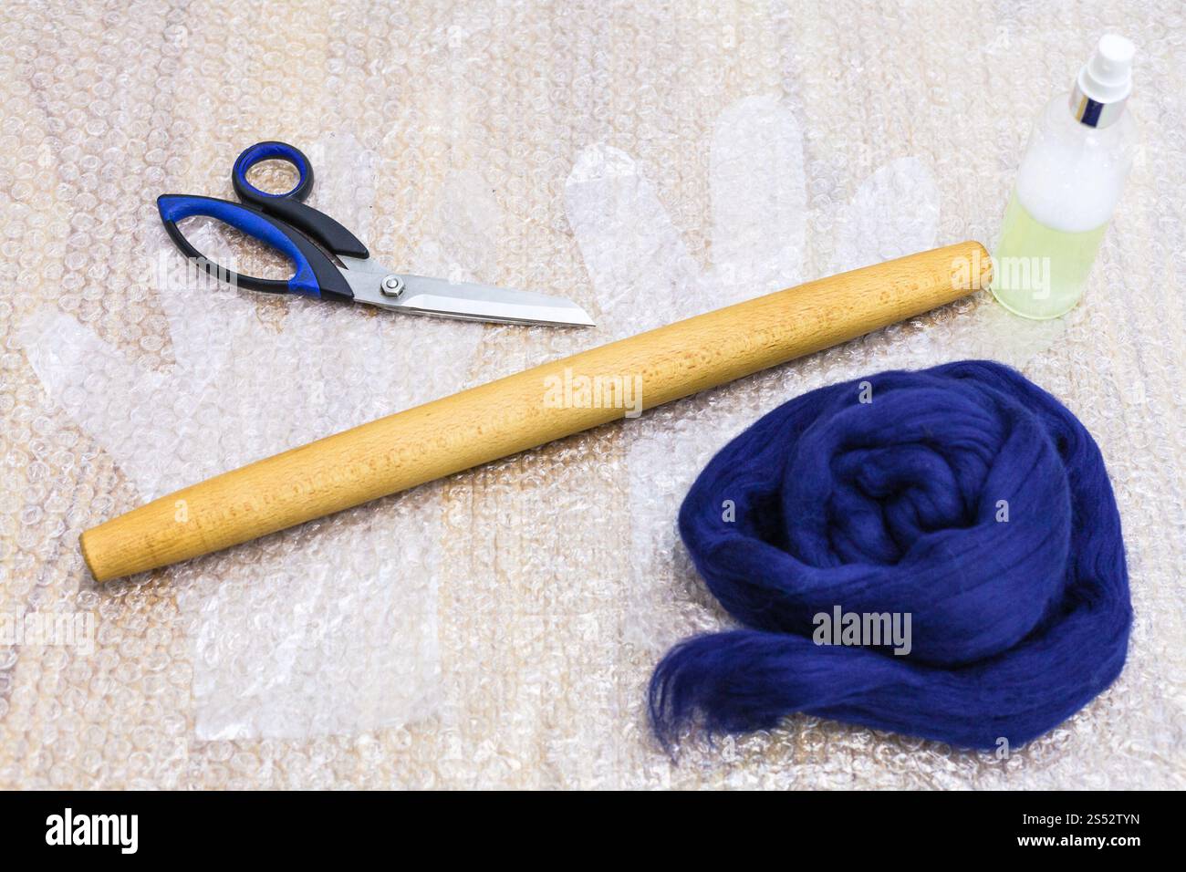 La main de l'atelier faisant un Gants polaire à partir de la laine de mouton mérinos bleu à l'aide de feutrage humide - ensemble de documents et d'outils pour faire du feutre sur carton mat Banque D'Images