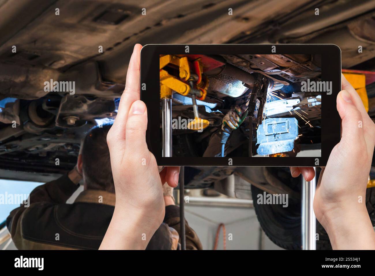 Concept de voyage - photographies de souder le silencieux du véhicule par soudure à l'argon au cours de la réparation en atelier sur smartphone Banque D'Images