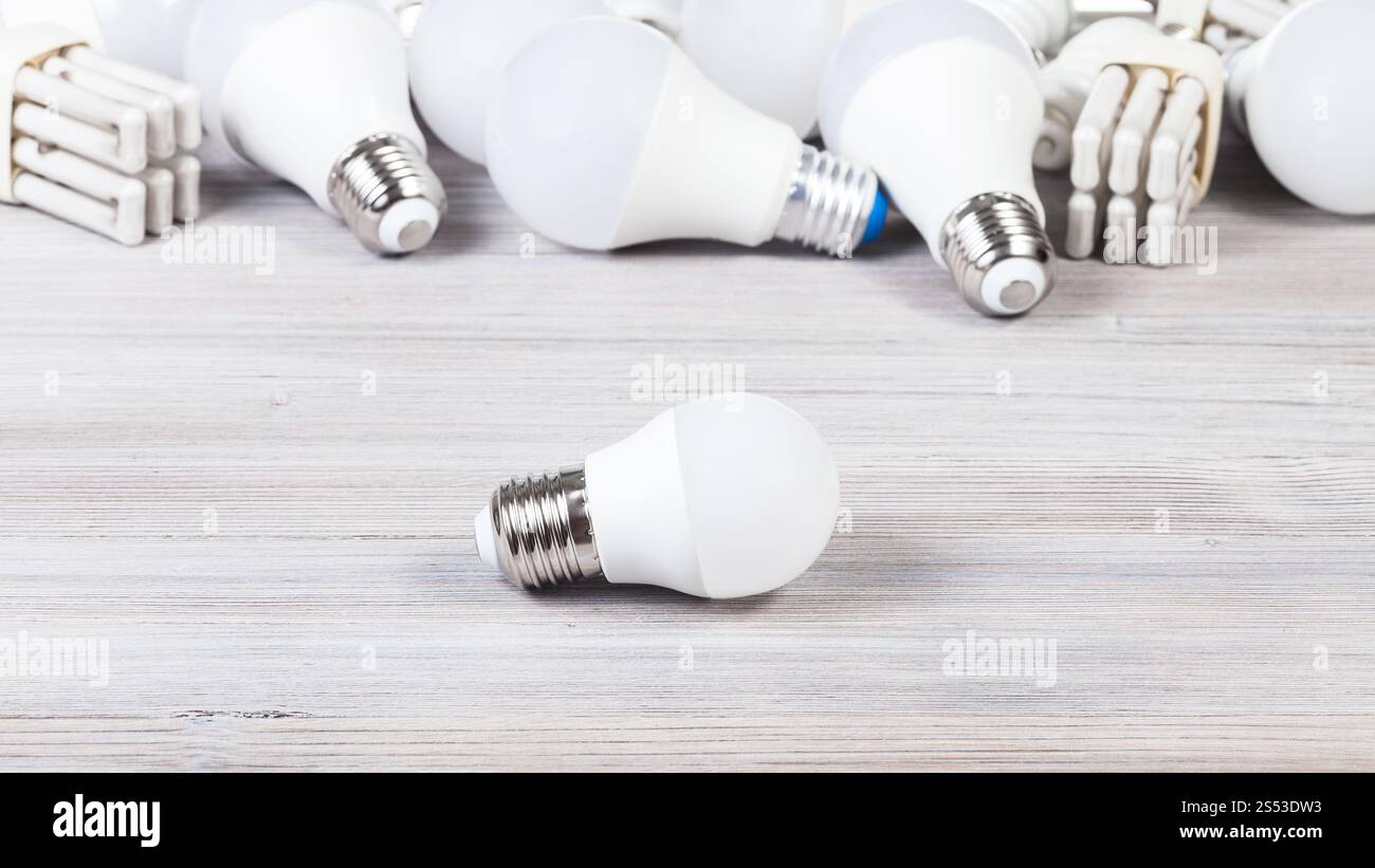 Une ampoule LED blanc et les lampes à économie d'énergie sur planche en bois gris Banque D'Images