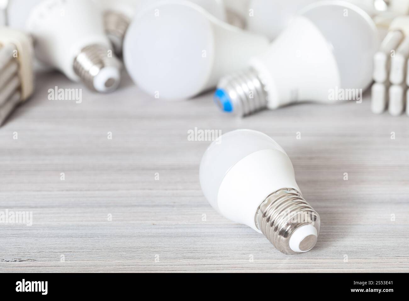 Une ampoule LED blanc close up et les lampes à économie d'énergie sur planche en bois gris Banque D'Images