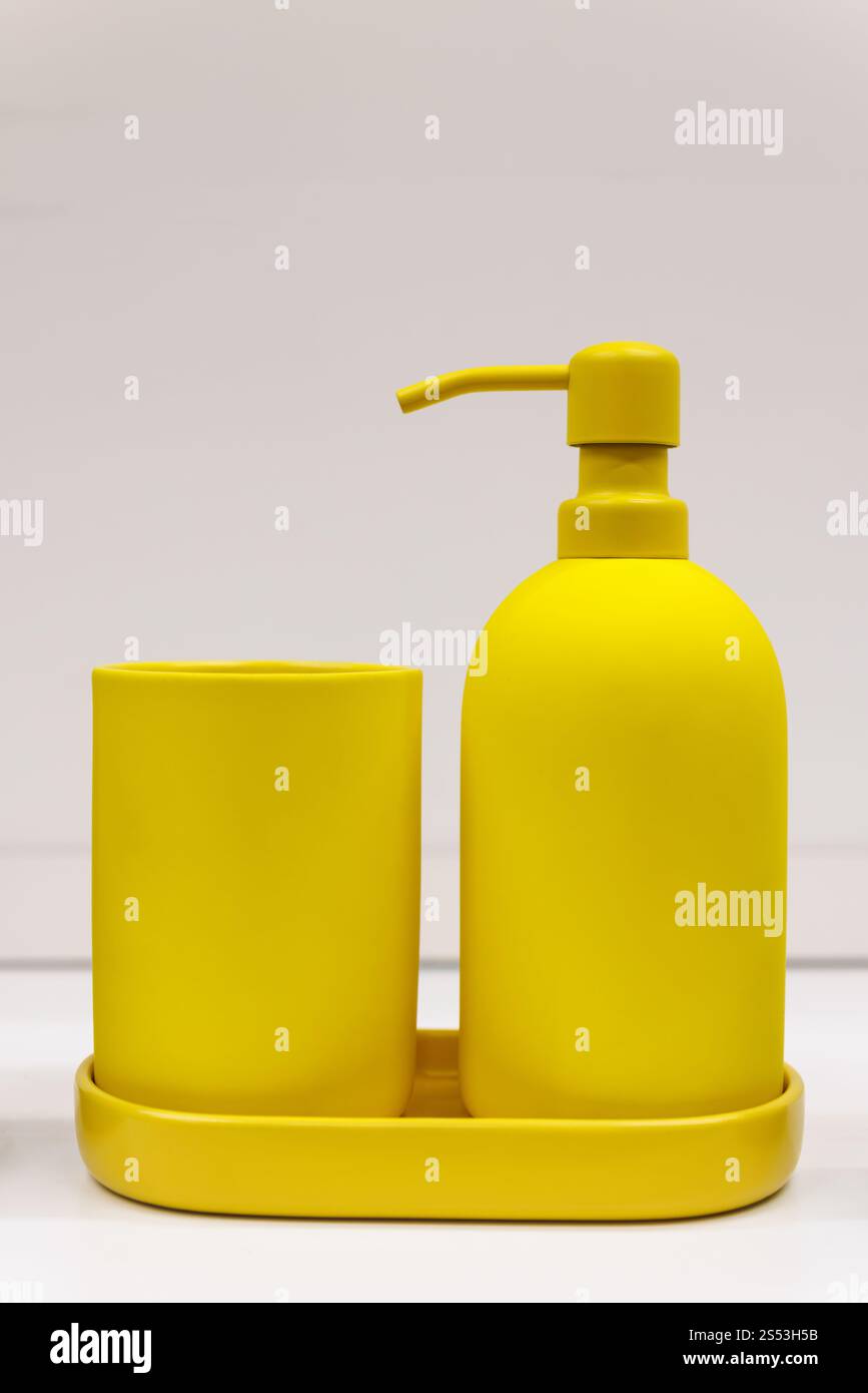Un ensemble de distributeurs de savon liquide jaune placés sur une étagère de salle de bain, ajoutant une touche de couleur et de style à l'espace. Banque D'Images Un ensemble de distributeurs de savon liquide jaune placés sur une étagère de salle de bain, ajoutant une touche de couleur et de style à l'espace. Banque D'Images