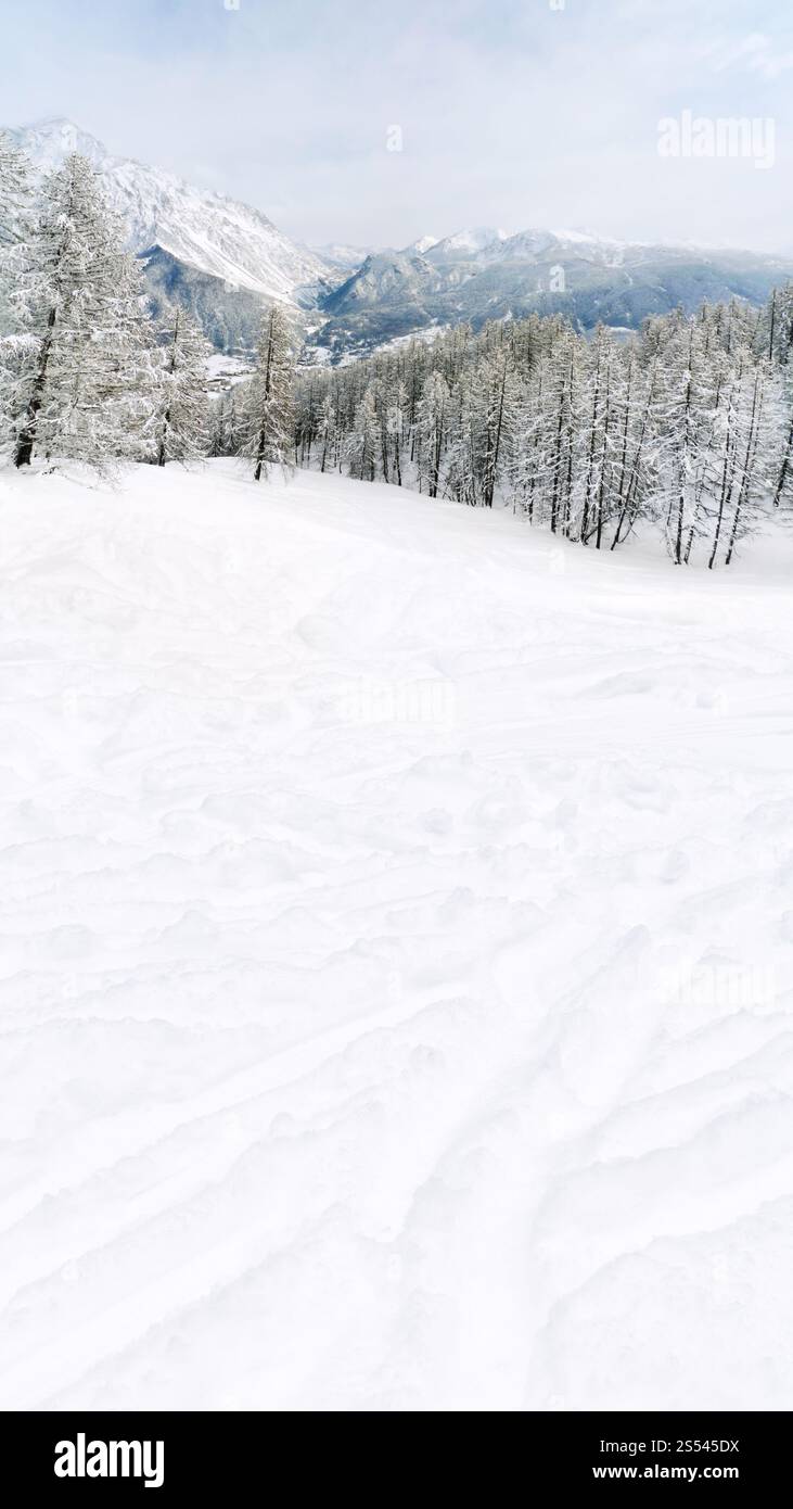 Pente de montagne couverte de neige et de montagnes des Dolomites sur horizon sur journée d'hiver Banque D'Images