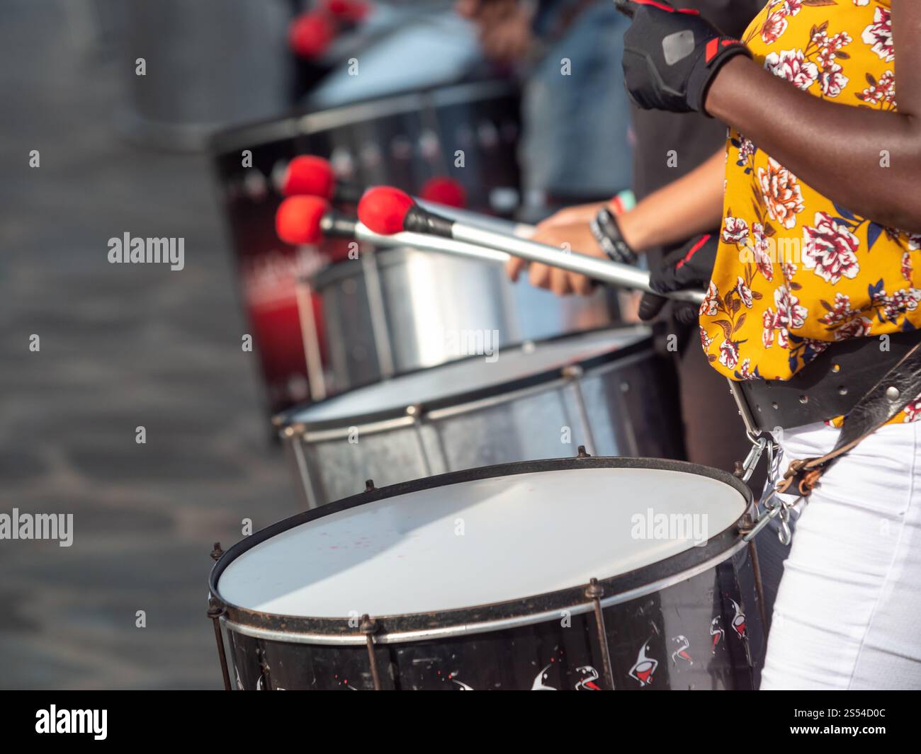 Gros plan photo d'une femme africaine à peau foncée jouant sur des tambours pendant une performance de rue. Gros plan d'une femme africaine à peau foncée jouant sur des tambours pendant Banque D'Images