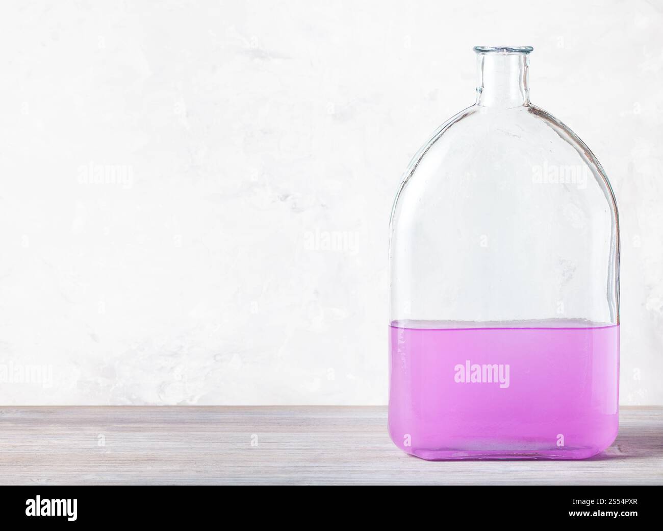 flacon en verre avec une solution d'aquarelle rose sur panneau de bois gris près du mur de béton gris. flacon avec solution d'aquarelle rose sur gris Banque D'Images