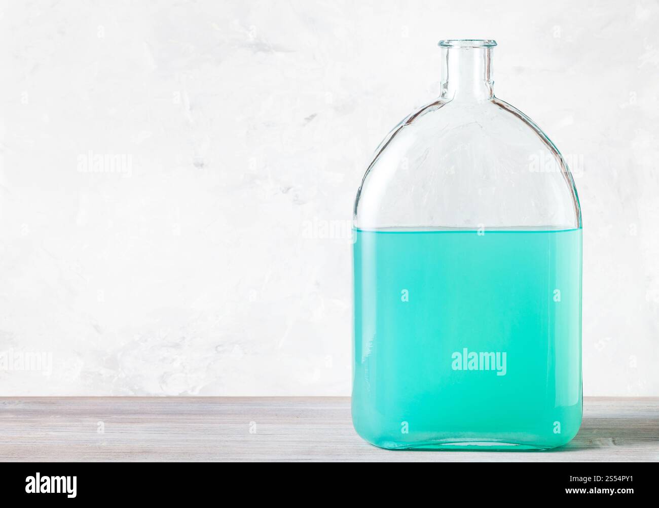 flacon en verre avec une solution d'aquarelle verte sur panneau de bois gris près du mur de béton gris. flacon avec solution d'aquarelle verte sur gris Banque D'Images