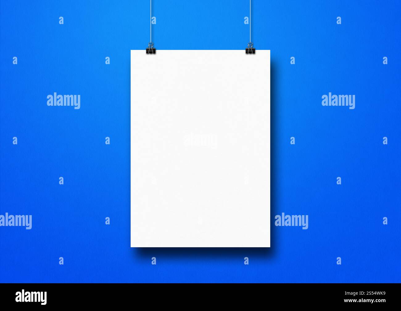 Affiche blanche accrochée sur un mur bleu avec des clips. Modèle de maquette vierge. Affiche blanche accrochée sur un mur bleu avec des clips Banque D'Images