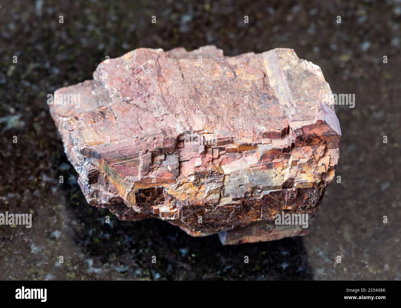 Gros plan de l'échantillon de minéral naturel de la collection géologique - roche sidéritique brute sur fond de granit noir de Cordoue, Andalousie, Espagne. brut Banque D'Images