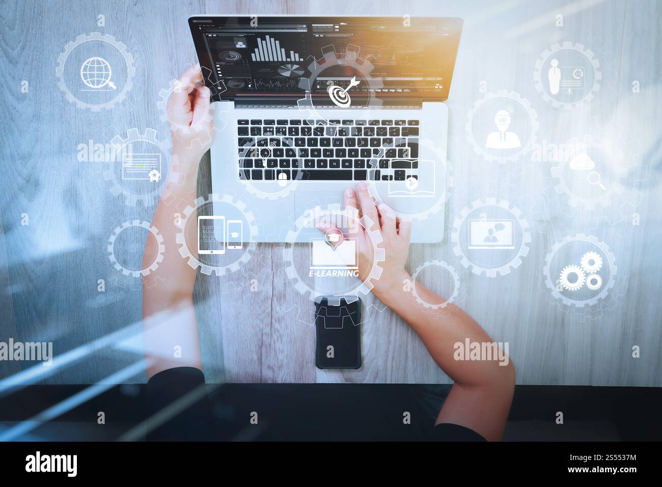 E-learning avec engrenages connectés diagramme connecté tableau de bord virtuel.vue de dessus de la main de concepteur travaillant avec un ordinateur portable et smartphone et Banque D'Images